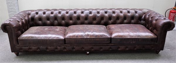 A large brown leather upholstered Chesterfield sofa, on turned supports, 300cm wide x 69cm high.