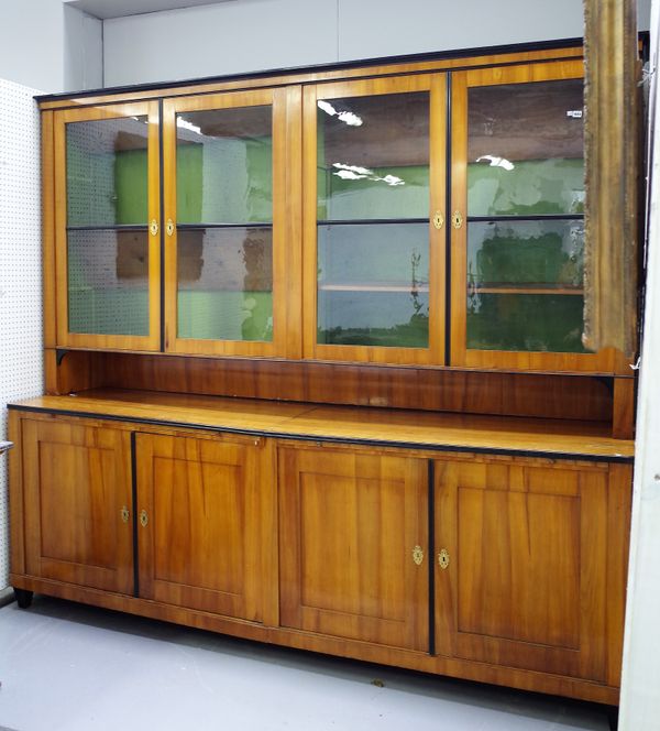 A large Biedermeier cherrywood and part ebonised library bookcase, with four glazed doors over recess and four panel cupboards, on tapering square sup