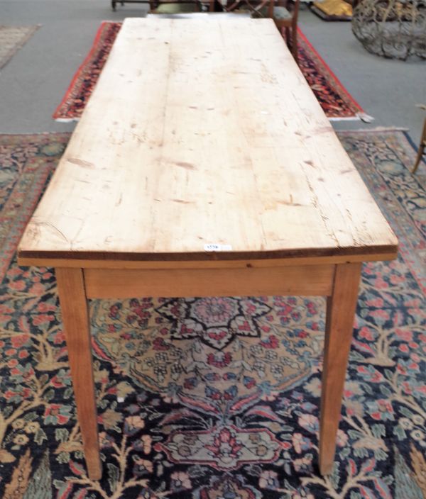 An early 19th century pine plank top kitchen table with frieze drawer on tapering square supports, 74cm wide x 221cm long.