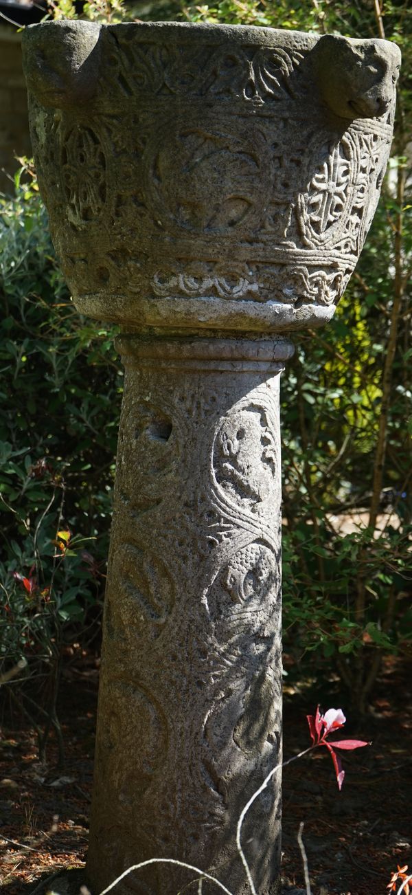 An Istrian carved stone font, 18th century, with four lion mask handles, carved meandering border, alternating palmette and animal ovals against a flo