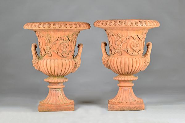 A pair of terracotta jardinières, with egg and dart rim over floral moulded twin handled bodied and fluted socles, 57cm diameter x 78cm high.  Illustr