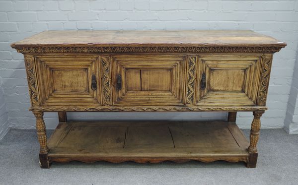 A 17th century style carved oak dresser base, with three recessed panel doors, on turned supports, united by potboard undertier, 164cm wide x 91cm hig