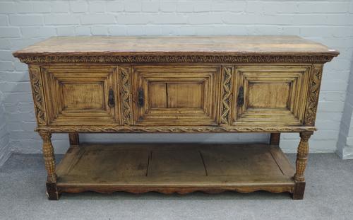 A 17th century style carved oak dresser base, with three recessed panel doors, on turned supports, united by potboard undertier, 164cm wide x 91cm hig