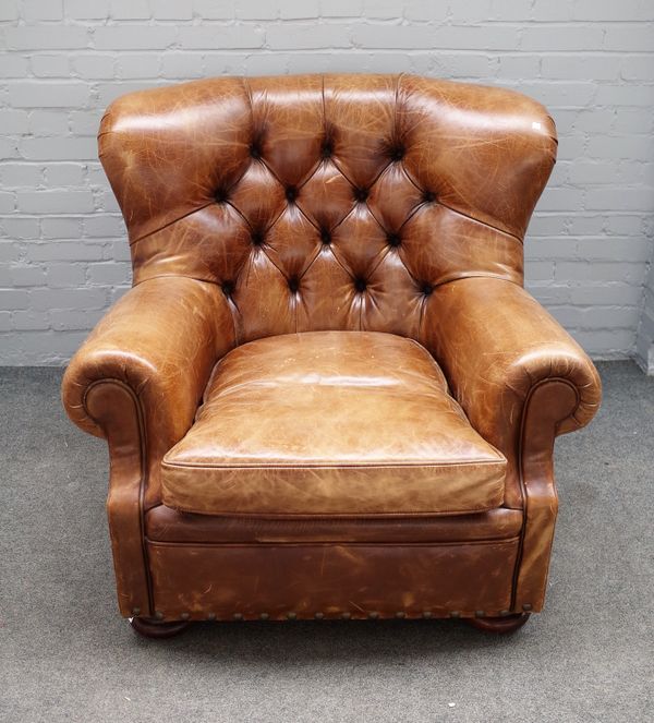 Ralph Lauren; a 20th century brown leather upholstered easy armchair on bun feet, 95cm wide x 96cm high and a matching footstool, 80cm wide x 38cm hig