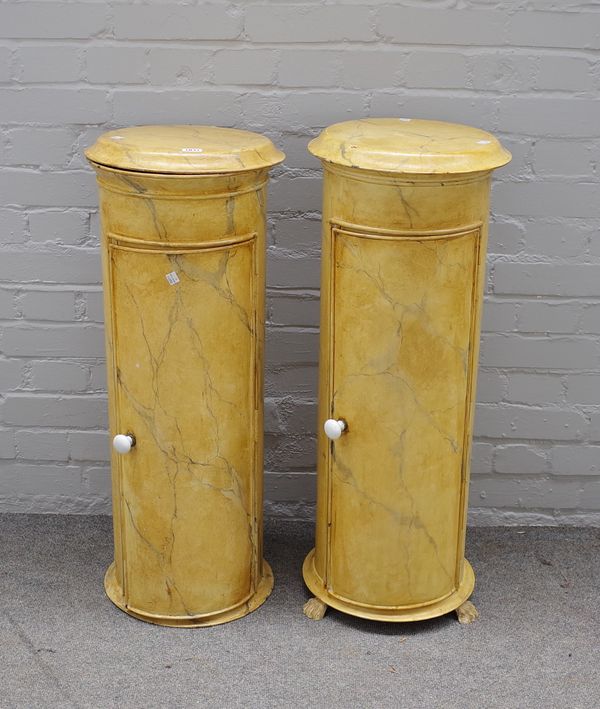 A pair of painted tôle simulated Sienna marble cylindrical pedestal pot cupboards, one lacking paw feet, 34cms diameter, taller 87cms high. (2)