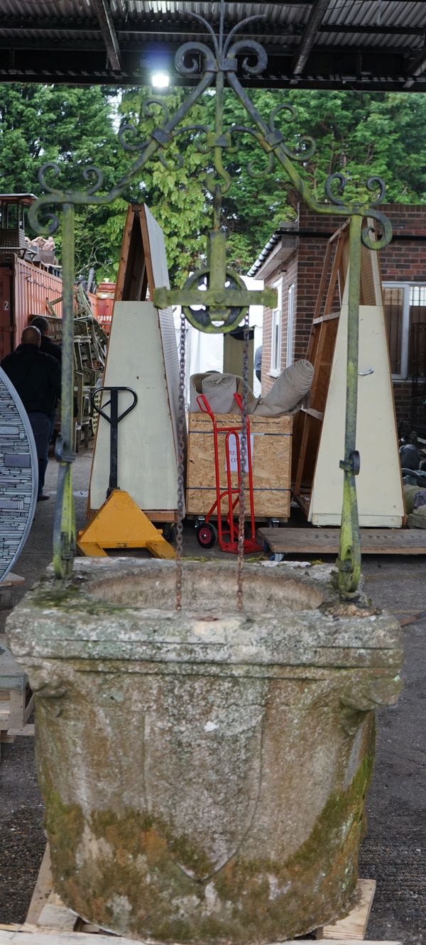 A Venetian stone well head, probably 17th century, with later wrought iron overthrow, carved to the sides, 74cm high, 85cms square.