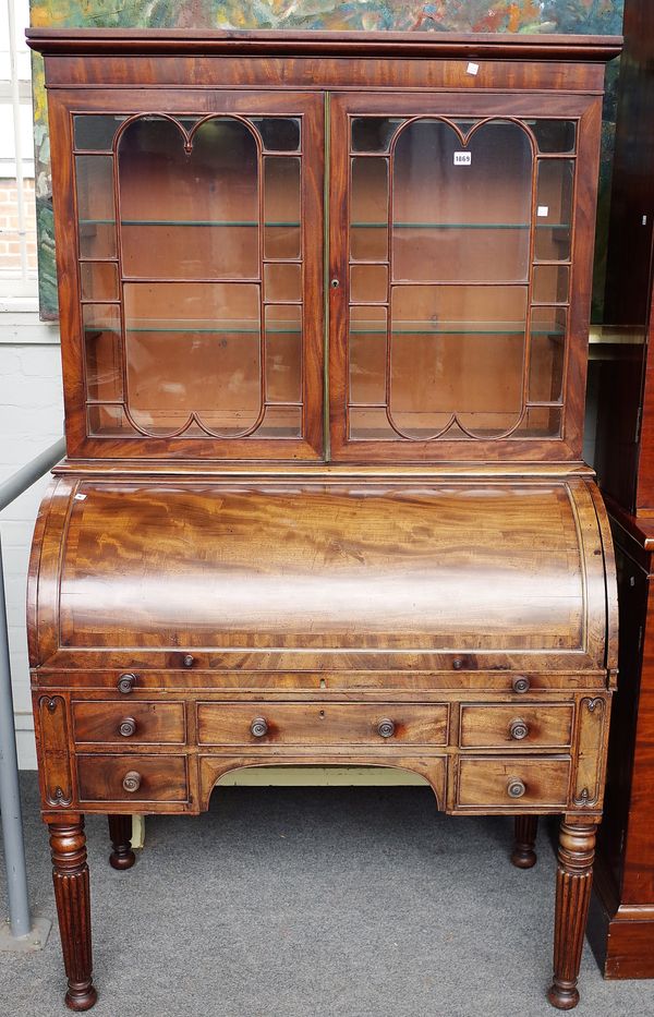 A George IV mahogany cylinder bureau bookcase, the pair of glazed doors over fitted interior and five frieze drawers on reeded supports, 109cm wide x