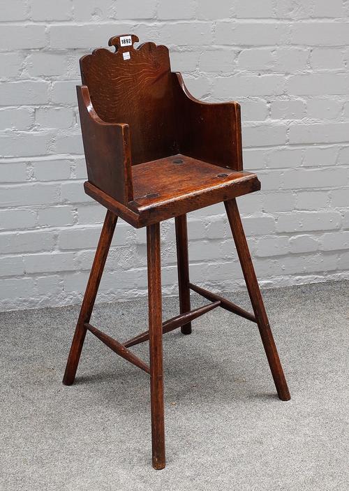 An early 19th century provincial oak child's highchair with solid back and seat on four staked supports, 44cm wide x 91cm high.