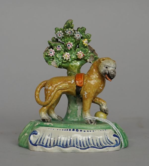 A Staffordshire pearlware figure of a lion, circa 1820, modelled standing before a flowering tree with one paw resting on a yellow ball, (a.f), 14cm.