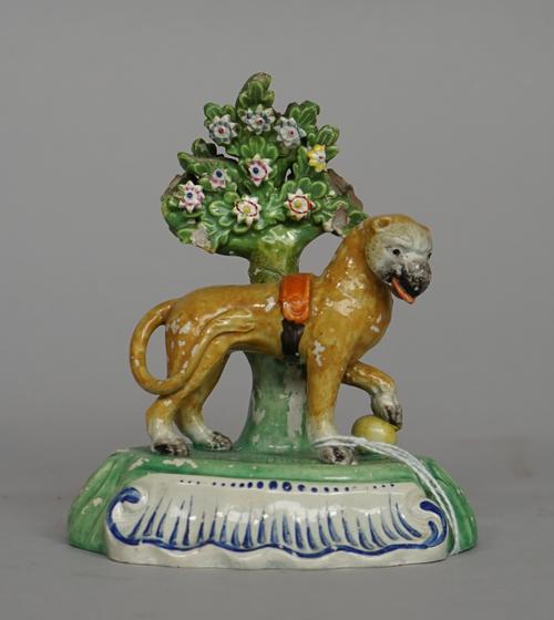 A Staffordshire pearlware figure of a lion, circa 1820, modelled standing before a flowering tree with one paw resting on a yellow ball, (a.f), 14cm.