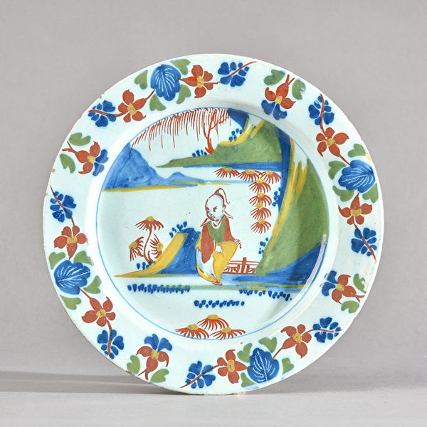 A London delftware polychrome small plate, circa 1750, painted with a seated Chinaman in a landscape, the border with flower garlands, 23cm. diameter.