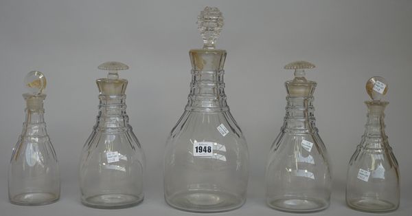 Five Prussian shaped decanters, early 19th each cut with flutes at the shoulders beneath ring necks, comprising; a magnum decanter, 26,5cm. high; a pa