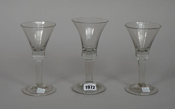 A plain-stemmed wine glass, mid 18th century, the bell bowl with tear in solid base, folded foot, 17.25cm. high; and two smaller plain-stemmed glasses