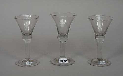 A plain-stemmed wine glass, mid 18th century, the bell bowl with tear in solid base, folded foot, 17.25cm. high; and two smaller plain-stemmed glasses