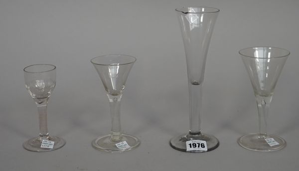 Four plain-stemmed wine glasses, mid 18th century, comprising; a tall glass with drawn trumpet bowl, two smaller drawn trumpet glasses and a glass wit