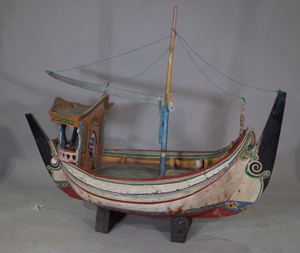 A scratch built wooden boat, early 20th century, polychrome painted over planked body, with a central mast and stand, 160cm wide.