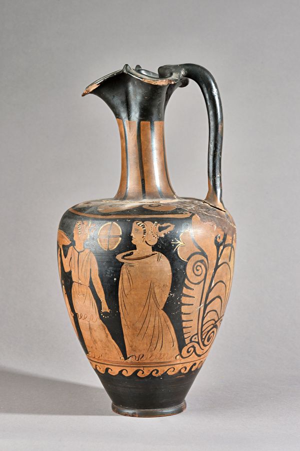 A companion red group Oinochoe, possibly Rhomboid group, depicting a naked youth seated on a rocky outcrop, dotted fillet in his hair, holding a plina