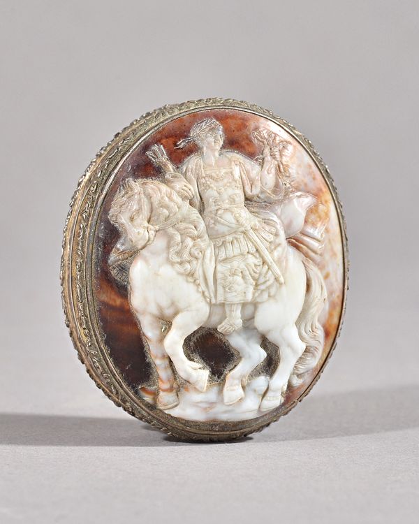 A silver mounted oval shell cameo hinge lidded snuff box, gilt within, the cover with a carved shell cameo depicting the figure of a warrior on horseb