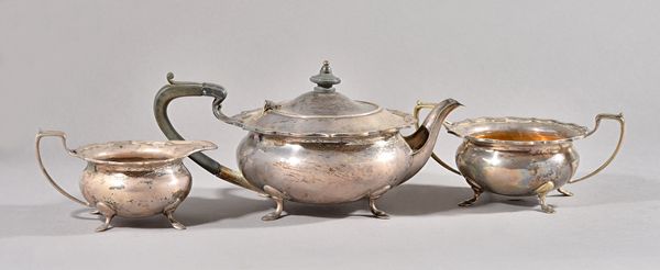 A silver three piece tea set, comprising; a teapot with black fittings, a twin handled sugar bowl and a milk jug, each piece of compressed circular fo