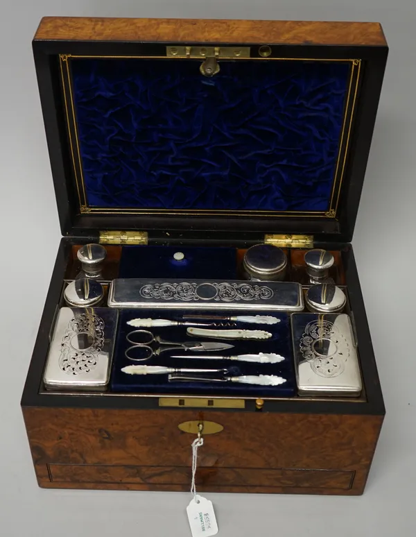 A lady's Victorian walnut travelling toilet box, the top fitted with eight silver plated metal topped toilet boxes and jars, various manicure implemen