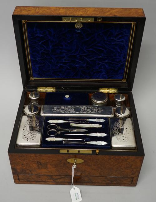 A lady's Victorian walnut travelling toilet box, the top fitted with eight silver plated metal topped toilet boxes and jars, various manicure implemen
