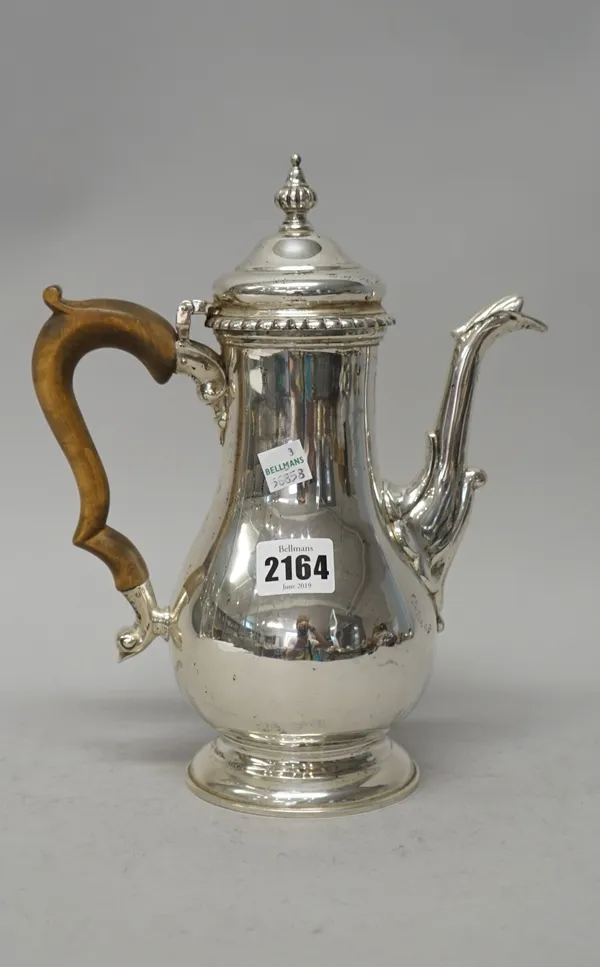 A silver coffee pot, of baluster form with a decorated spout and with a fluted finial to the hinged lid, in the 18th century taste, with a wooden hand