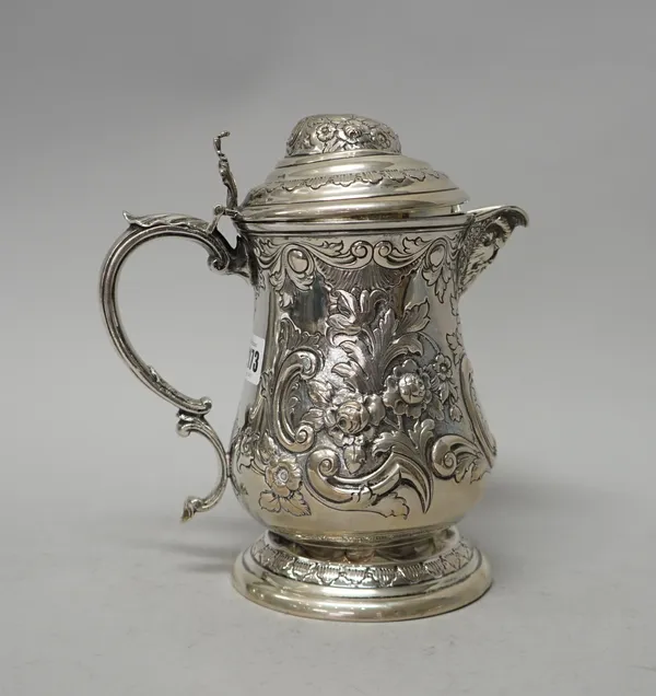 An Italian hinge lidded wine jug, of baluster form, with a foliate capped thumbpiece, the spout formed as a mask, raised on a circular foot, detailed