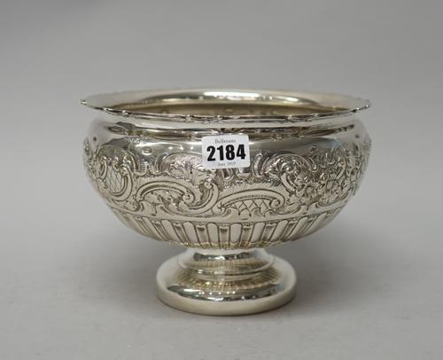 A late Victorian silver bowl, of circular form, the body embossed with a wide floral, foliate and scrolling band above semi-fluted decoration, on a ci