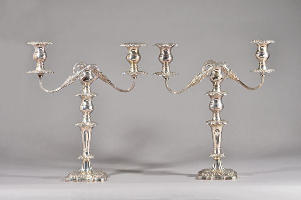 A pair of silver three light table candelabra, each with scrolling fluted arms and on a shaped square base, with foliate and floral cast borders, with