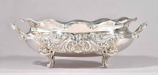 An Italian twin handled large table centrepiece bowl, of oval form, the body embossed with bold scrollwork within a wavy rim, raised on four scrolled