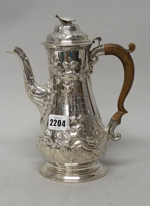 An early George III silver coffee pot of baluster form, later embossed and chased with floral and foliate scrolling decoration, the hinged lid with a