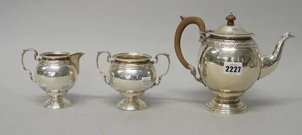 A George V silver three piece tea set, comprising; a teapot, a twin handled sugar bowl and a milk jug, each piece of globular form and with embossed d