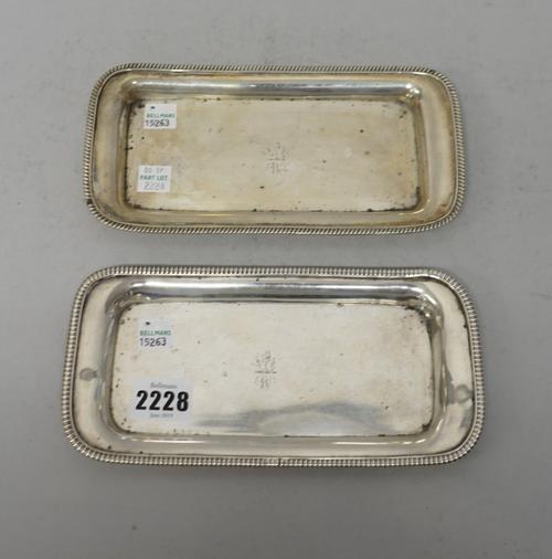 A near pair of George III silver candle snuffer's trays, of rounded rectangular form, each with gadrooned borders and engraved family crest and initia