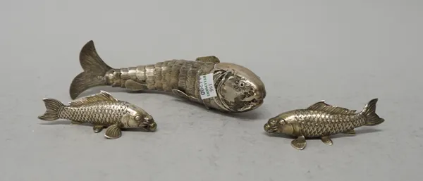 A .900 silver Middle Eastern fish of articulated form (lacking one hardstone eye), 18cms long; and a pair of Japanese white metal Koi fish ornaments (