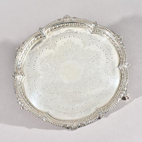 A Victorian silver salver, of shaped circular form, having a leaf capped gadrooned border, the centre engraved with scrollwork decoration, raised on t
