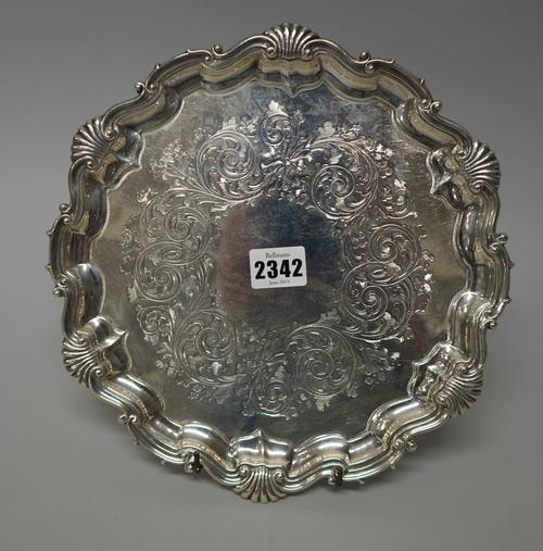 A Victorian silver salver of shaped circular form, having a shell capped pie-crust border, the centre engraved with foliate and scroll decoration, rai