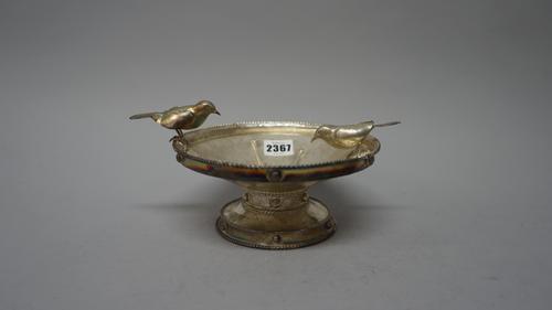 A silver pedestal bowl, of circular form, the bowl applied with two cast models of birds otherwise decorated with wire-work borders and roundels, in t