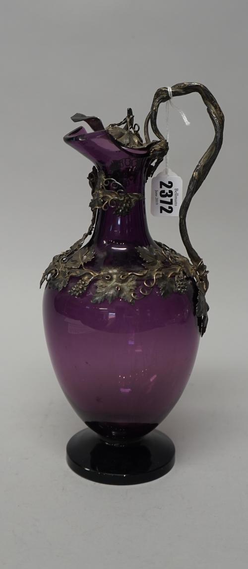 A Victorian silver mounted purple glass claret jug, the mount and hinged lid decorated with fruiting vine and with a naturalistic formed handle, by Jo