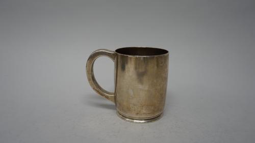 A silver mug, of plain cylindrical form, with a C scroll handle and raised on a circular spreaded foot, inital and date engraved, London 1945, weight