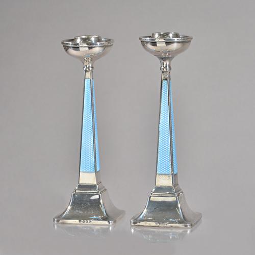 A pair of George V silver and pale blue enamelled candlesticks, the tapering faceted stems raised on outswept square base's, by Charles S Green & Co,