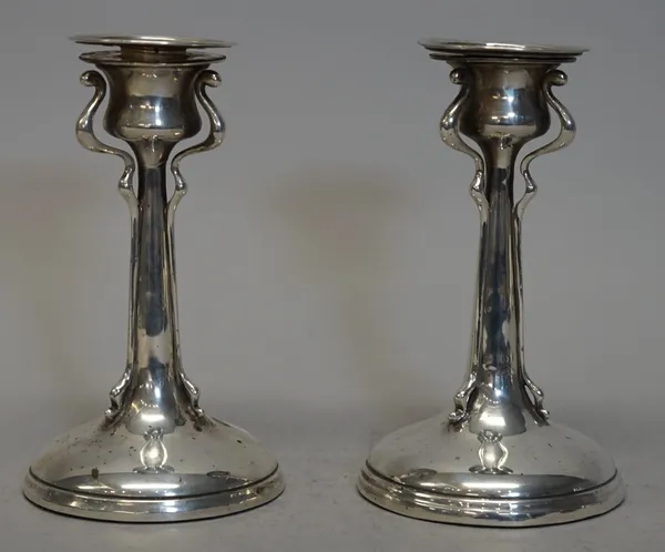A pair of Art Nouveau silver candlesticks, the tapered stems with three shaped supports raised on circular bases, with detachable sconces, by T Wooley