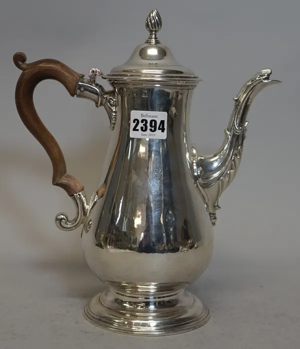 An early George III silver coffee pot, of baluster form, raised on a plain circular foot, the hinged lid with a wrythen knop finial, with a wooden han