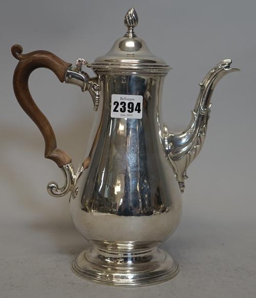 An early George III silver coffee pot, of baluster form, raised on a plain circular foot, the hinged lid with a wrythen knop finial, with a wooden han