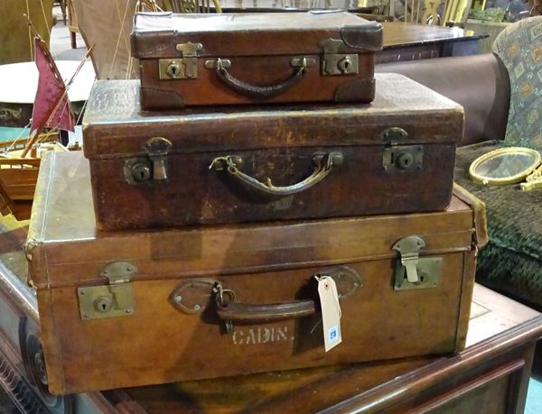 A group of three early 20th century leather suitcases, the largest 70cm wide x 27cm high, the smallest 35cm wide x 10cm high, (3).