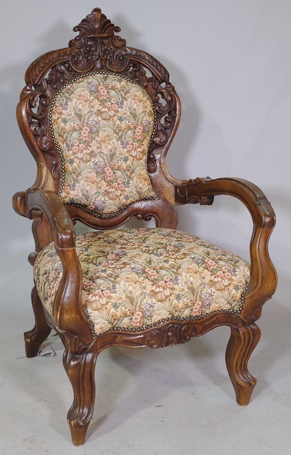 A late 19th century continental oak open armchair with carved crest on cabriole supports.