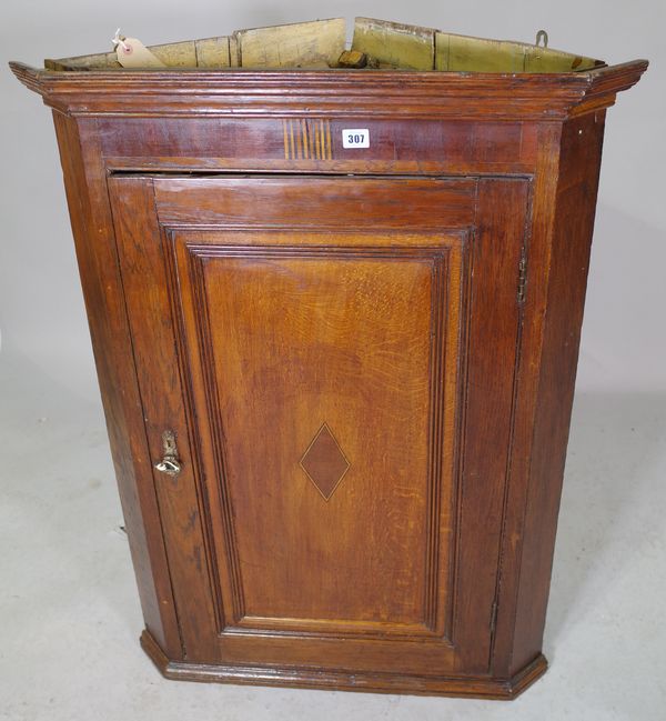 A George III oak hanging corner cupboard, with single panelled door, 77cm wide x 105cm high   34