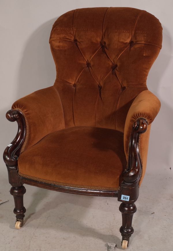 A Victorian mahogany framed armchair with brown button back upholstery.