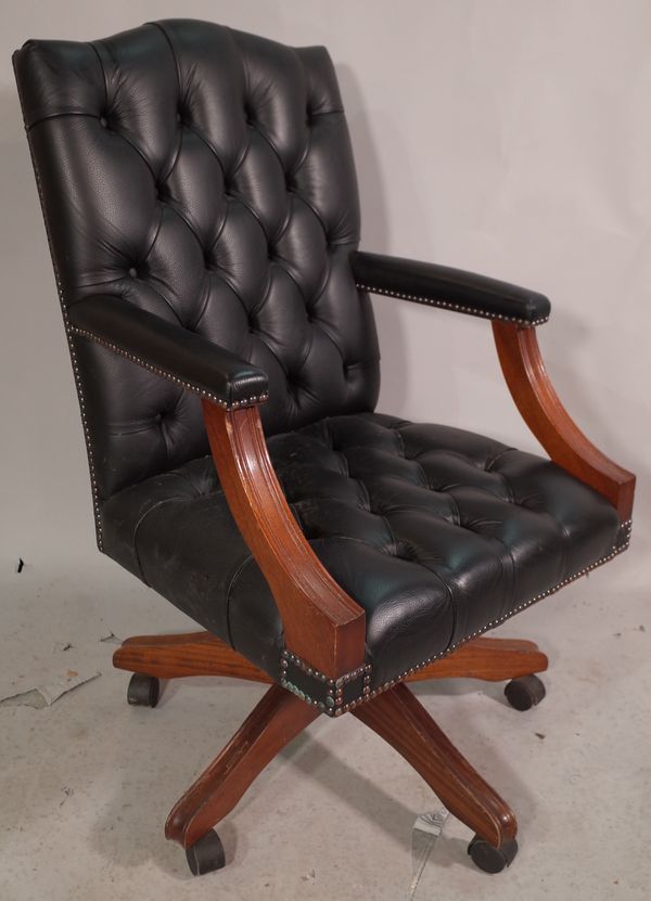 A 20th century swivel office open armchair, with faux black leather button back upholstery.