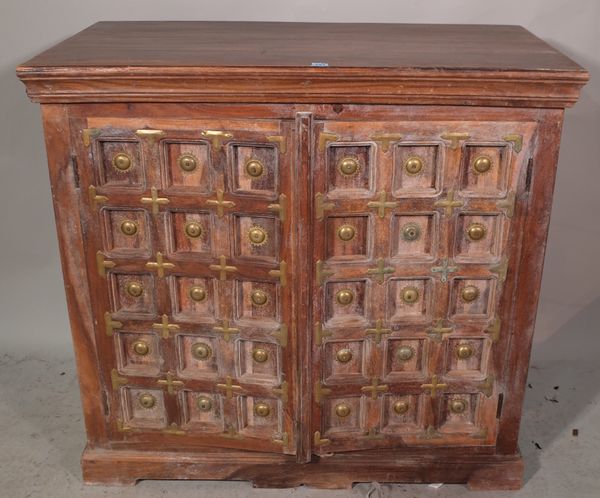 A 20th century Indian hardwood side cabinet with studded panelled doors, 107cm wide x 102cm high.