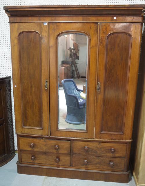 A Victorian mahogany triple wardrobe with mirrored door on plinth base.